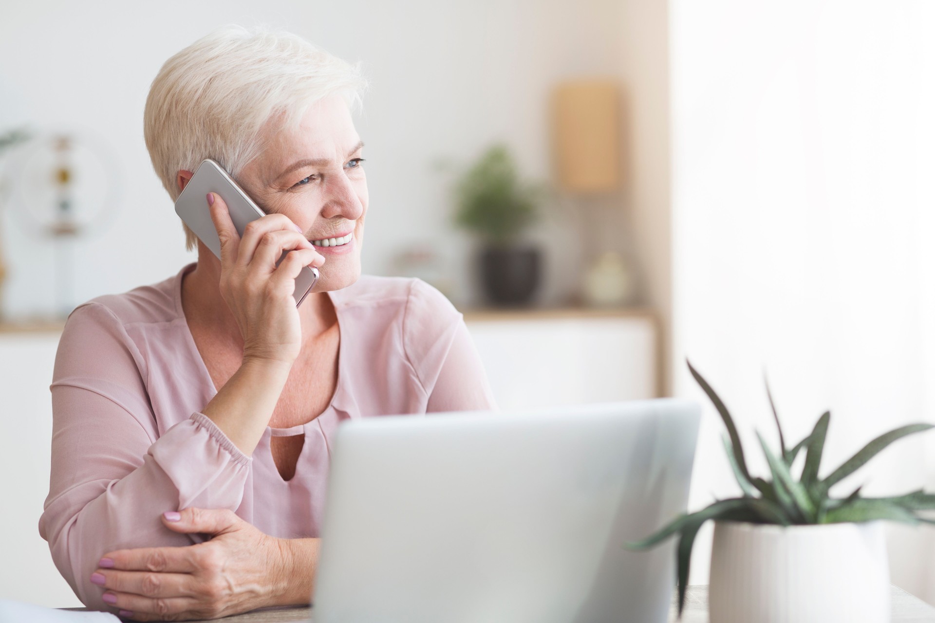 Vieille femme positive parlant par le téléphone avec des clients