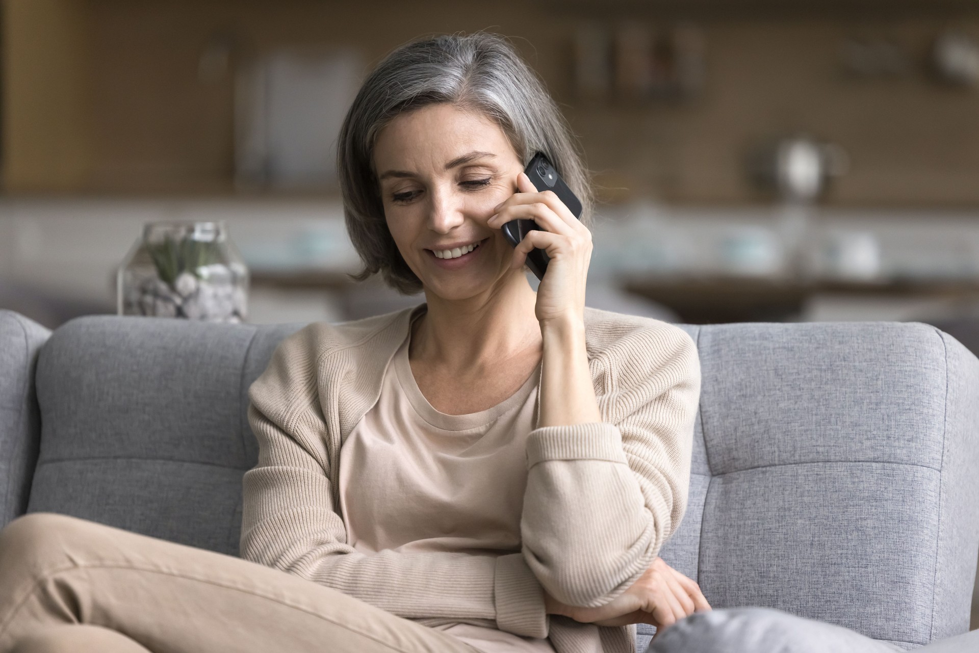 Une femme souriante mène une conversation agréable et distante sur un smartphone