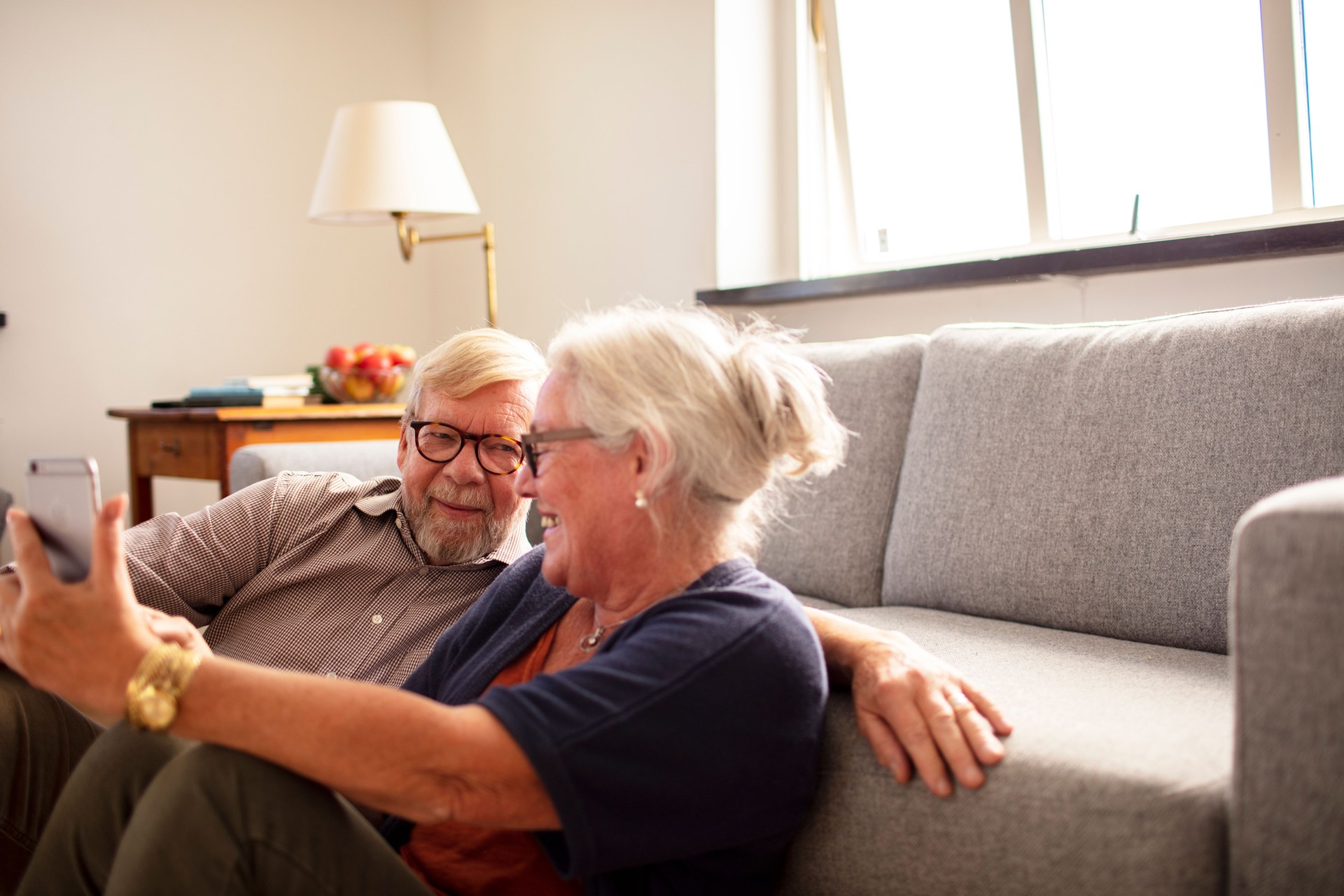 Heureux couple de personnes âgées utilisant leur téléphone à la maison
