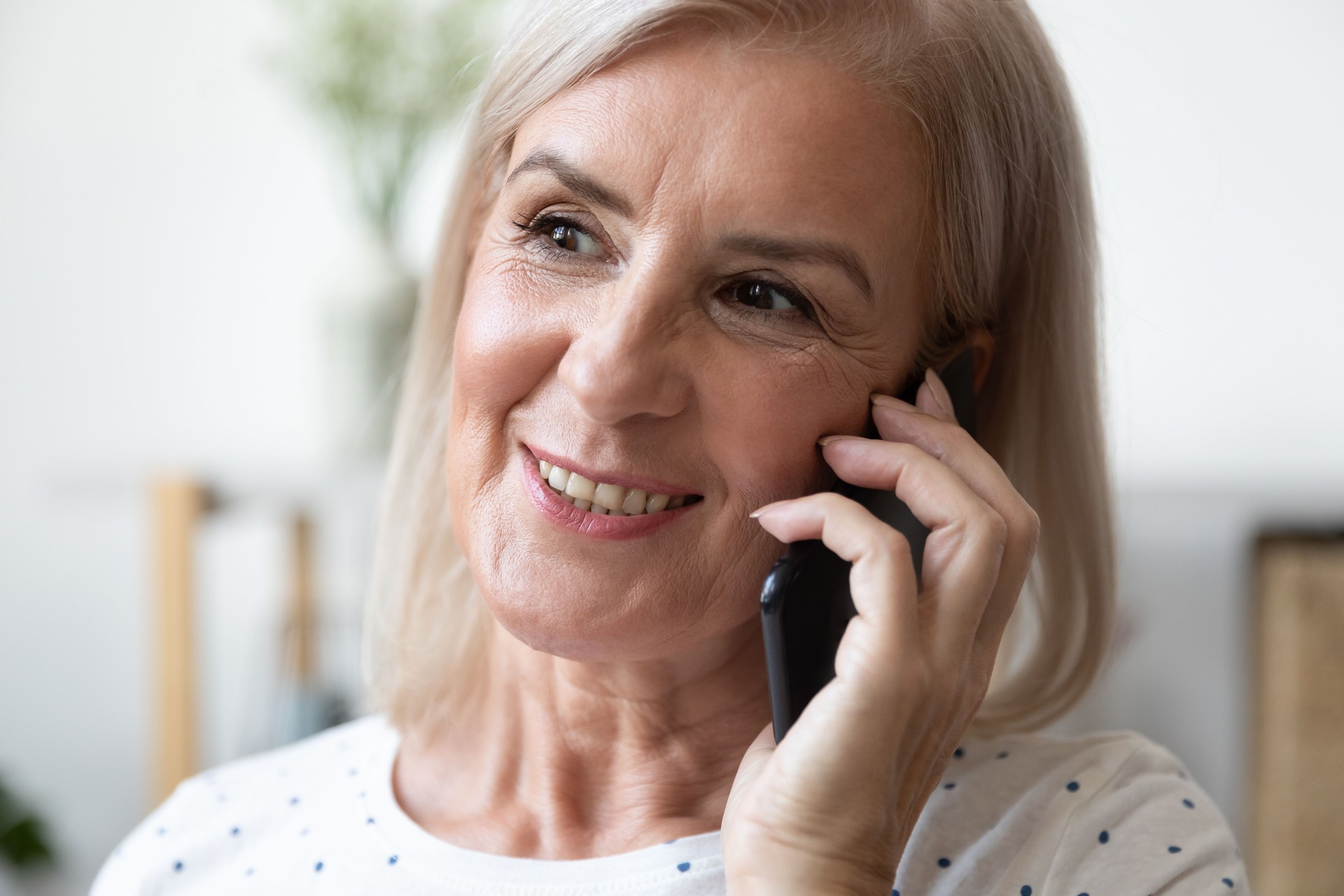 Femme aînée heureuse parlant sur le smartphone avec des enfants adultes.